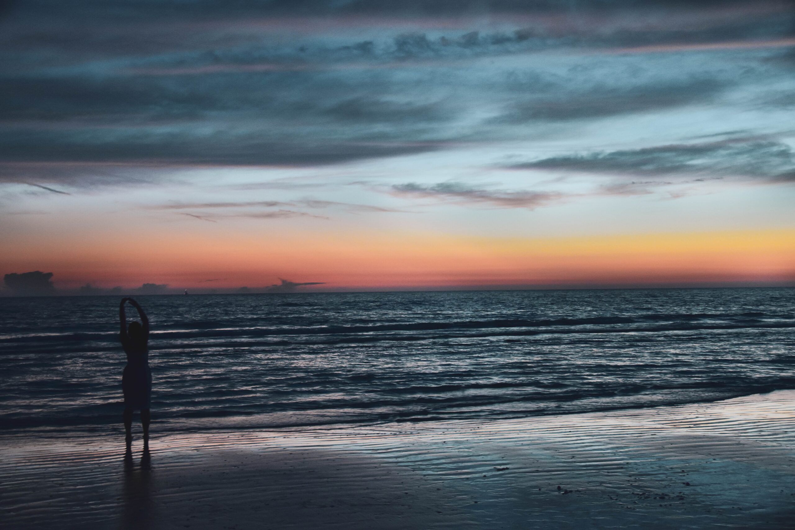 woman on a beach alone at sunset