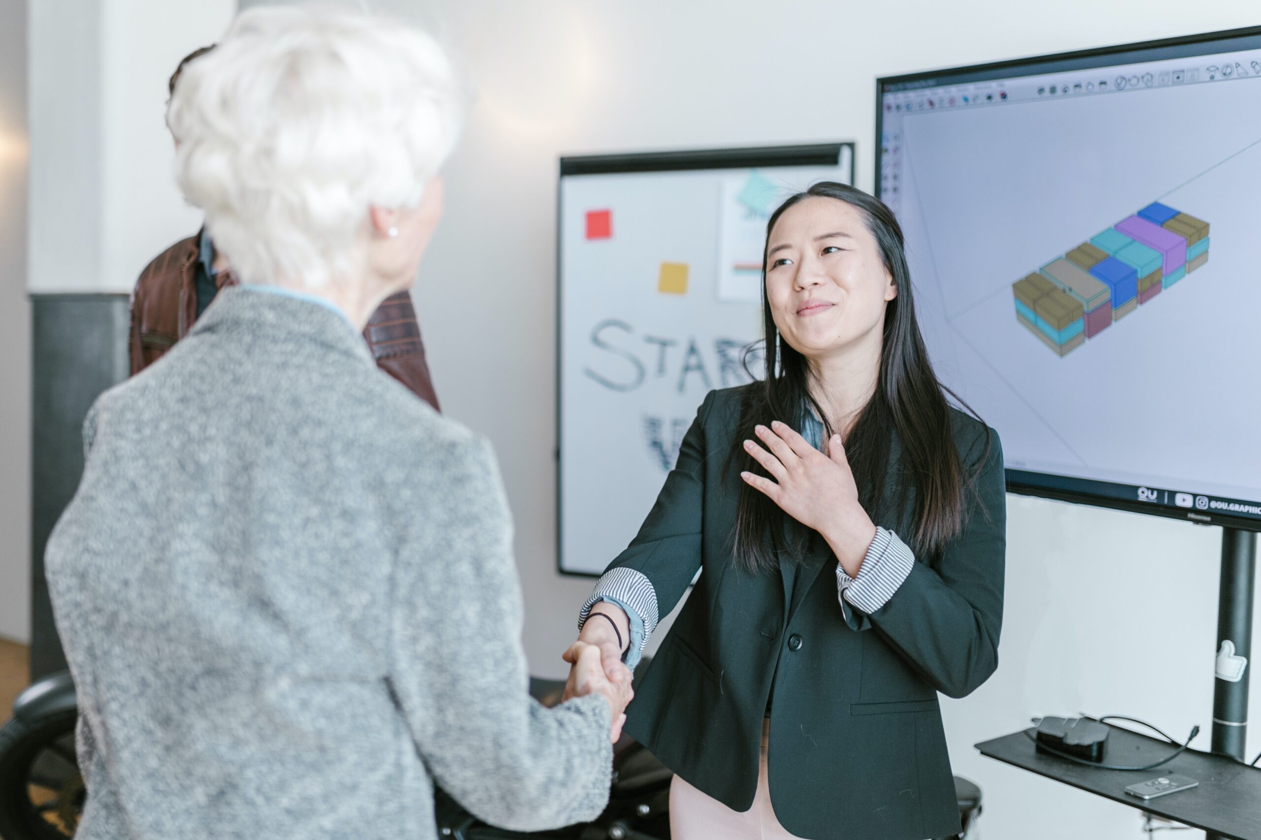 asian woman shaking hands with woman with white hair