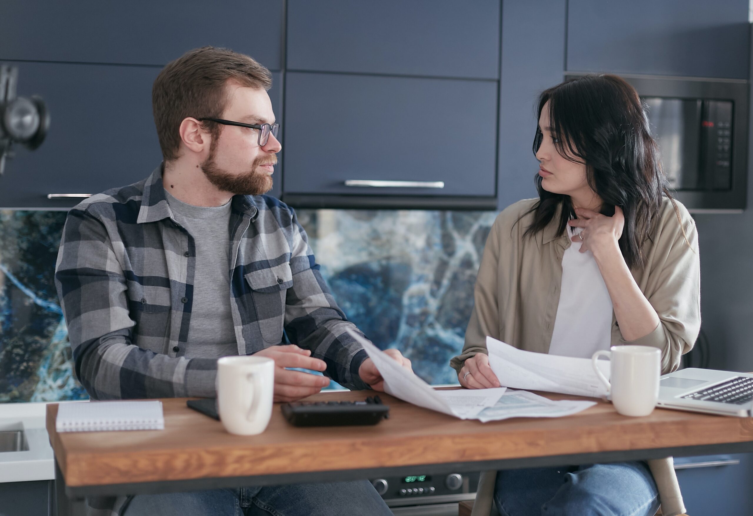 couple with laptops talking at a table