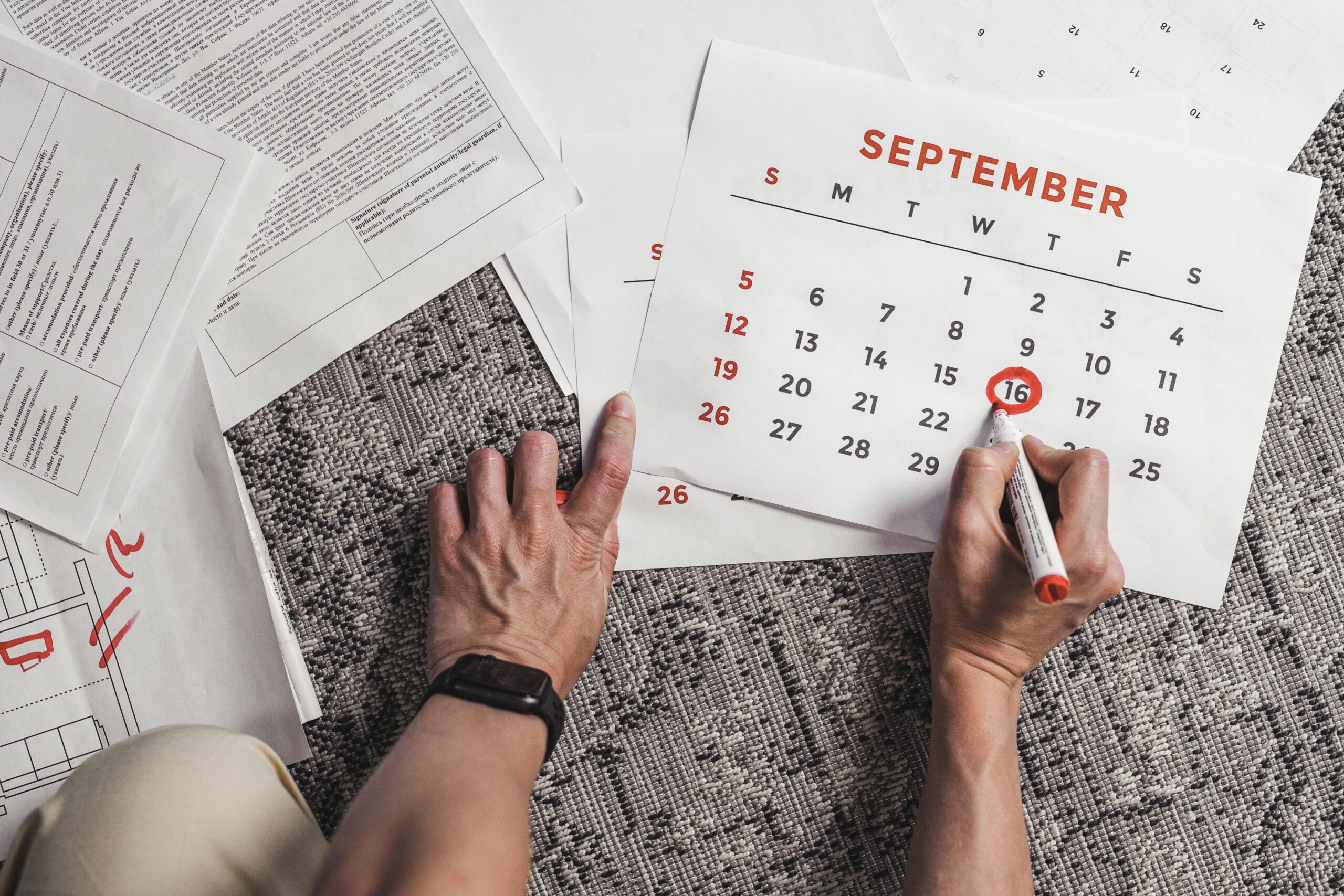 hand circling a date on a calendar with a red pen