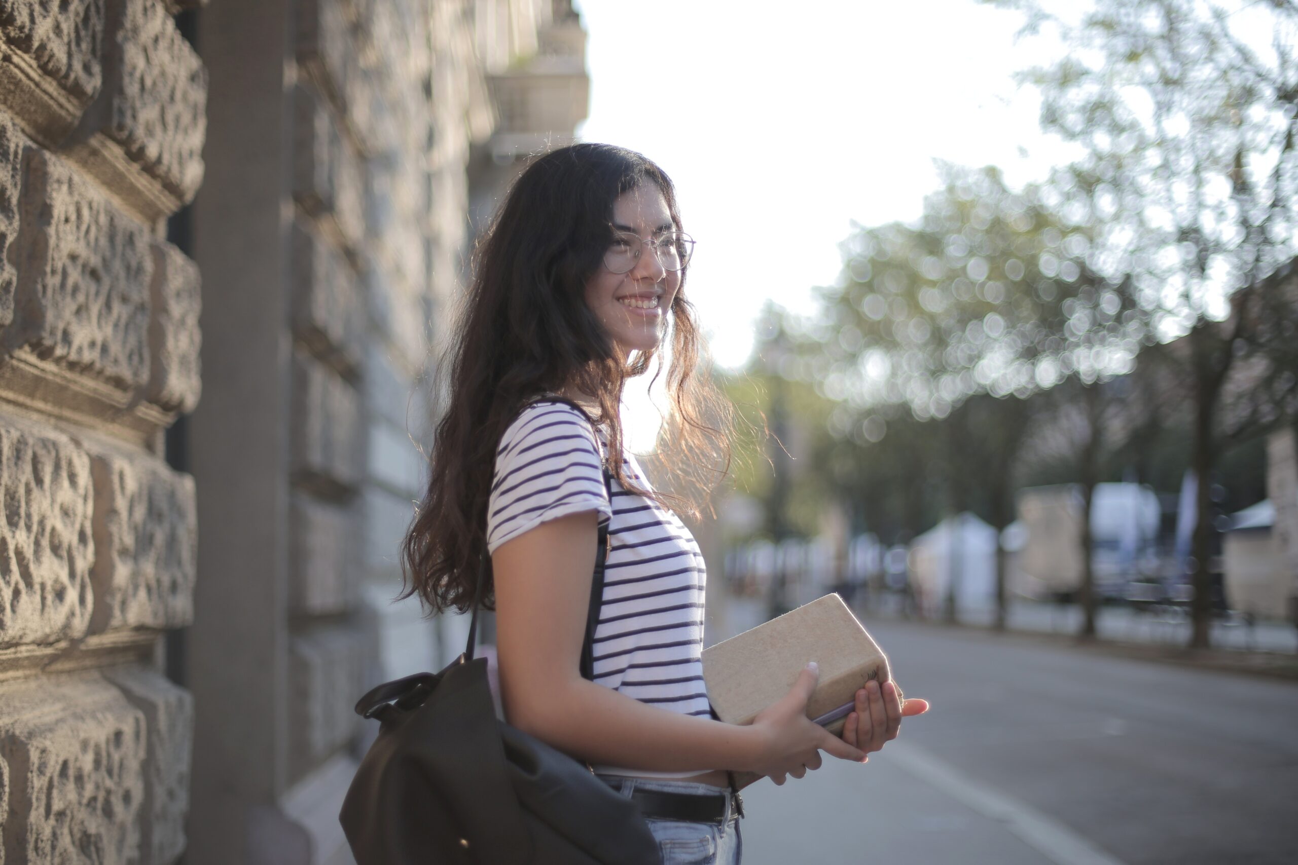 ethnic woman in glasses smiling and holding a book