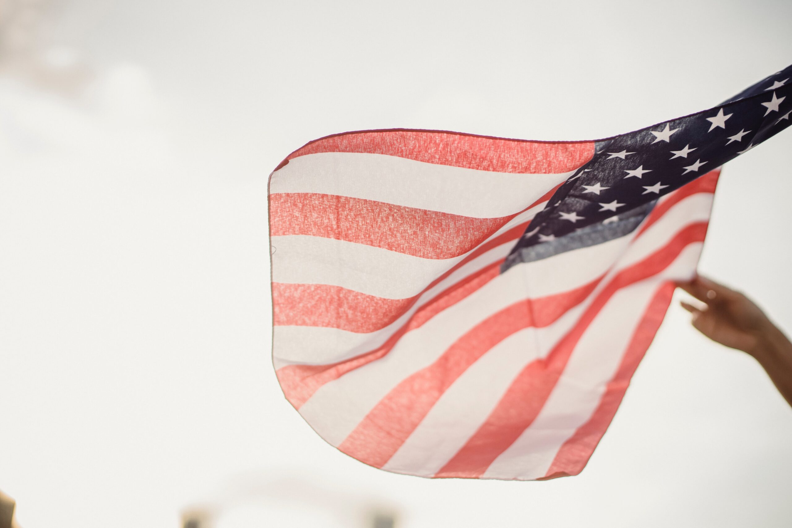 american flag waving with a hand beside it